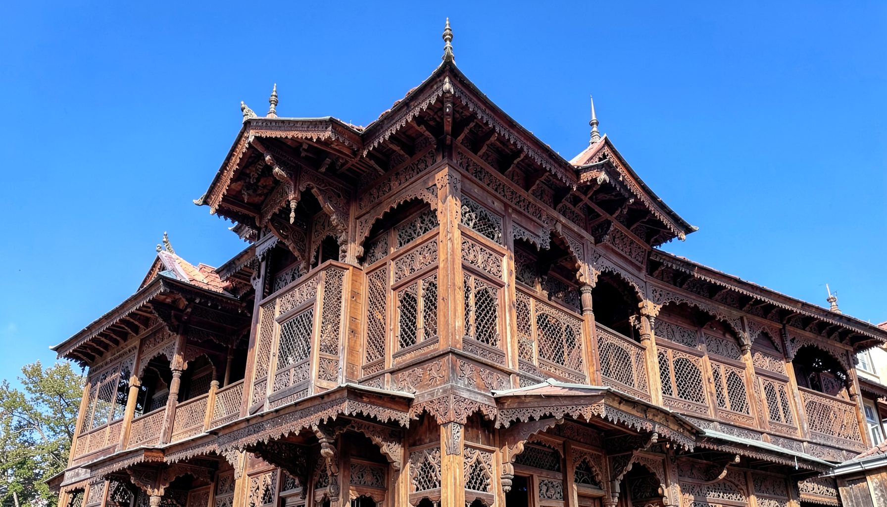 Ornate wooden architecture of a traditional Kashmiri shrine with intricate carvings against a bright blue sky